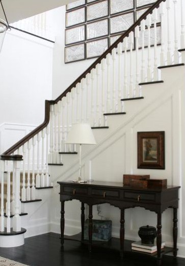 Hallway flooring ideas. HIGH STREET MARKET (2011) Monochromatic hallway. The achromatic colour scheme in this hallway has been successfully done by staining the floor black, and keeping the scheme balanced by painting the banister black to match and adding pictures in dark frames to draw the eye towards the top of the stairs.