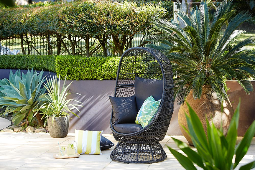 wicker egg chair in leafy garden