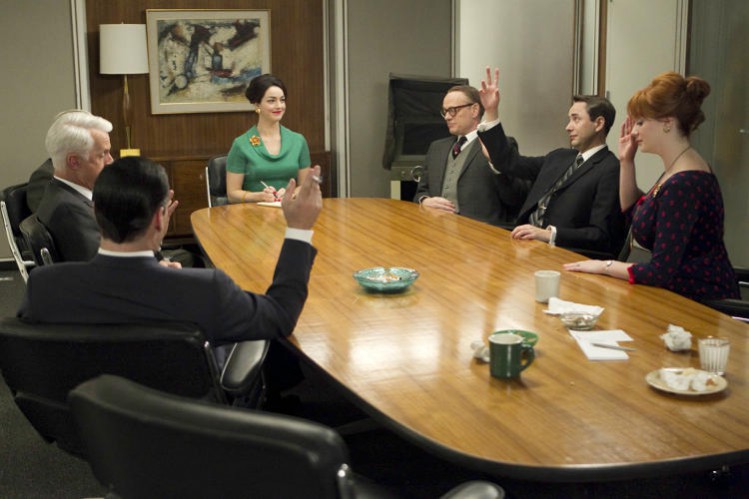 Mad Men Set Design influencing Interior Design Trends. Eames Conference Table, staff sit around the table in Eames Time-Life chairs. 